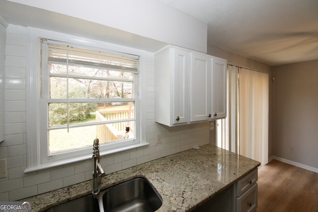 kitchen featuring light stone countertops, sink, dark hardwood / wood-style floors, decorative backsplash, and white cabinets