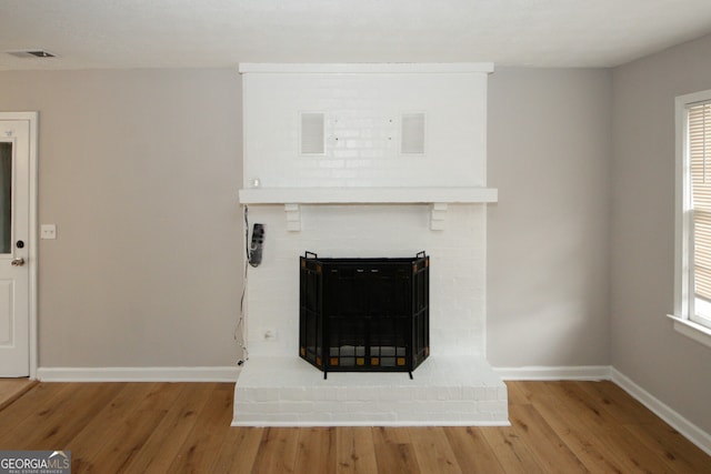 interior details with wood-type flooring and a brick fireplace