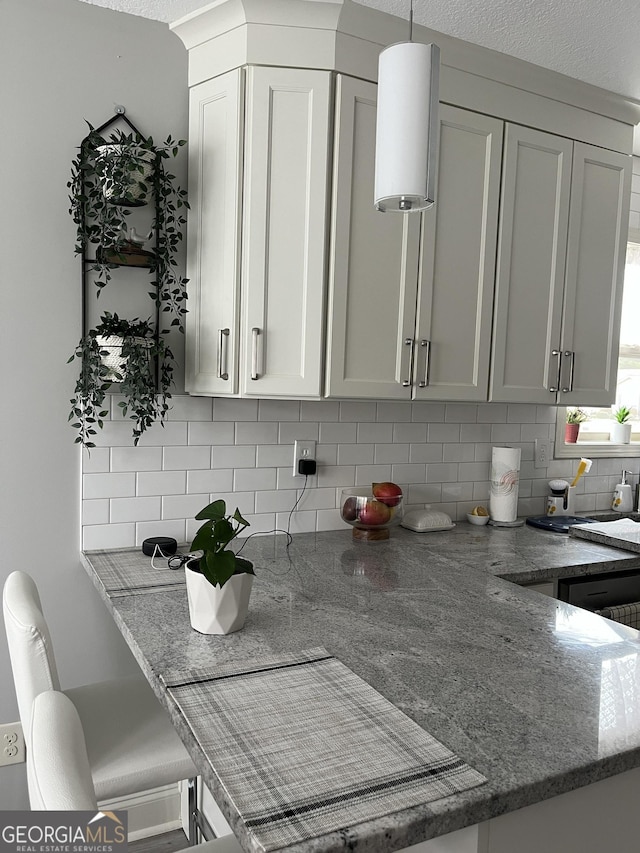 kitchen with a breakfast bar, stone countertops, and tasteful backsplash