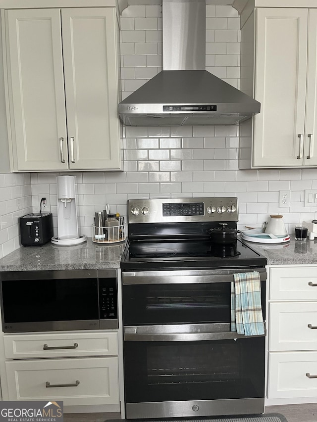 kitchen with appliances with stainless steel finishes, white cabinetry, backsplash, and wall chimney exhaust hood