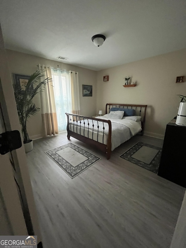 bedroom featuring visible vents and wood finished floors