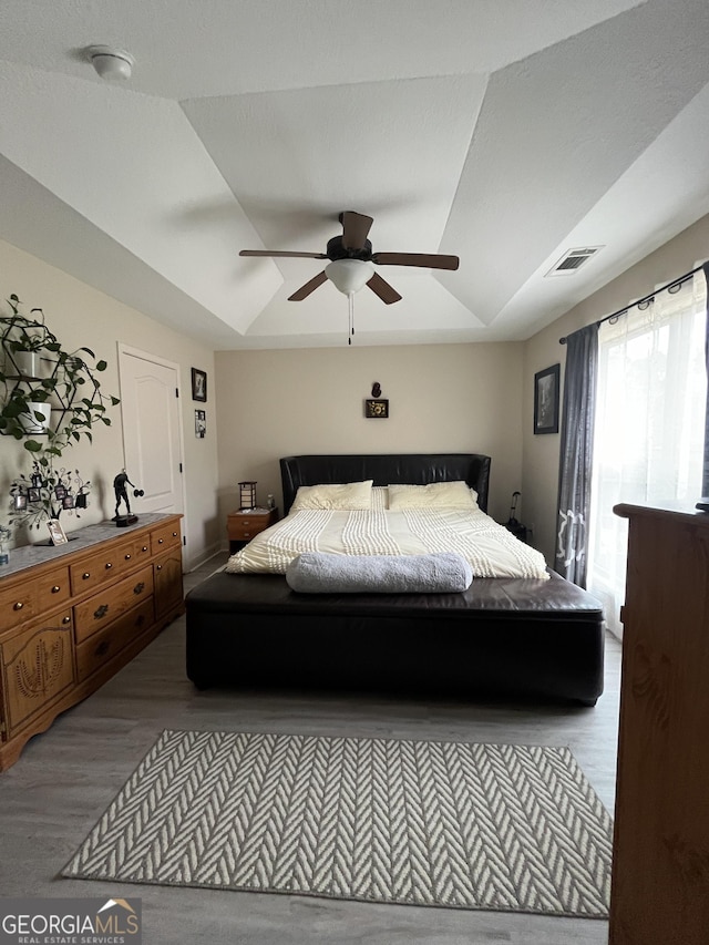 bedroom with lofted ceiling, a ceiling fan, visible vents, and wood finished floors