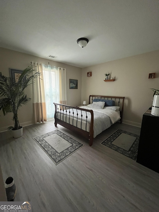 unfurnished bedroom featuring baseboards, visible vents, and wood finished floors