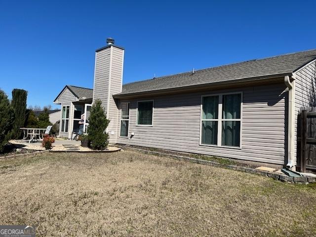 back of house with a patio area and a chimney