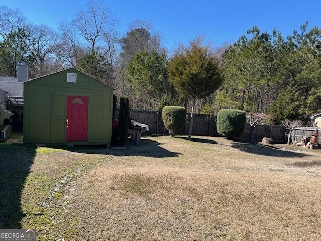 view of yard featuring a fenced backyard, a storage unit, and an outdoor structure