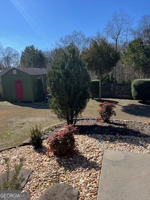 view of yard with an outbuilding, fence, and a storage shed