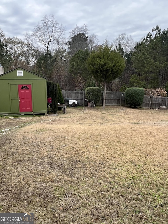 view of yard with fence, a storage unit, and an outbuilding