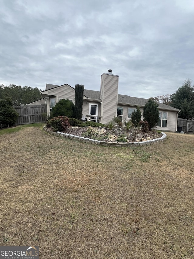 ranch-style house featuring a chimney, fence, and a front lawn