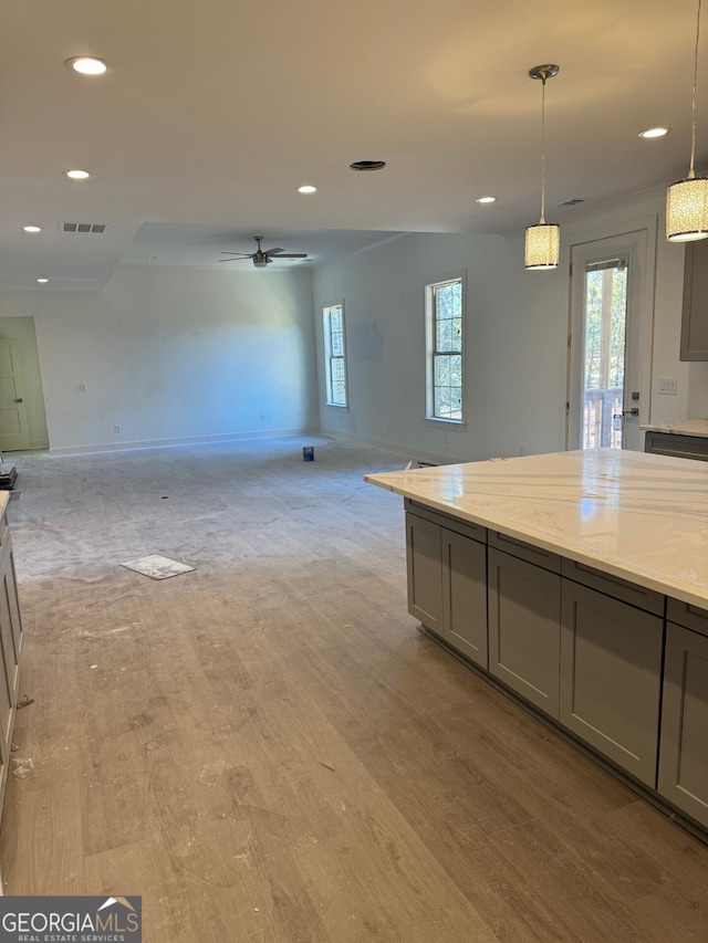 kitchen with ceiling fan, gray cabinets, light wood-type flooring, decorative light fixtures, and light stone counters