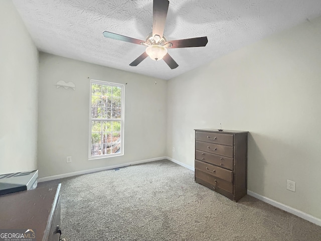 unfurnished room featuring carpet flooring, ceiling fan, and a textured ceiling