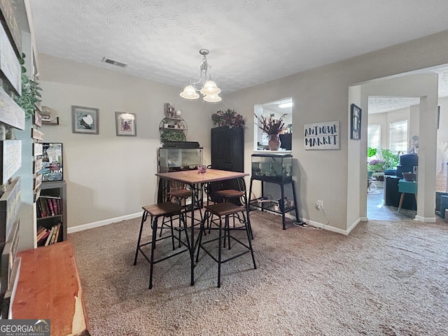 carpeted dining area featuring a textured ceiling and a notable chandelier