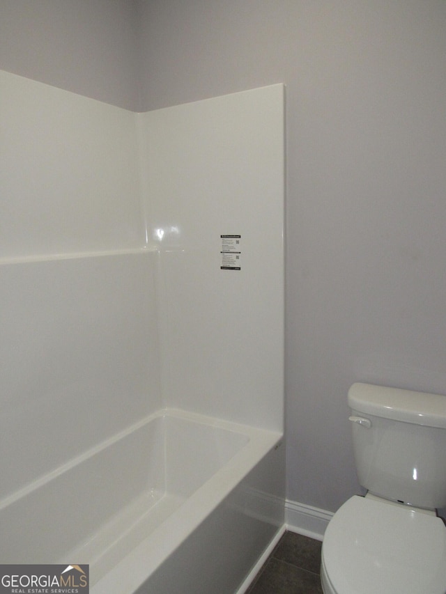 bathroom featuring a washtub, tile patterned flooring, and toilet