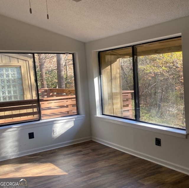 empty room with dark hardwood / wood-style flooring, a textured ceiling, and a wealth of natural light