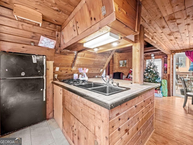 kitchen with black fridge, kitchen peninsula, sink, and wooden ceiling