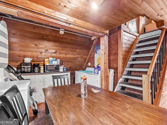 dining room featuring washer / dryer, dark hardwood / wood-style floors, wooden ceiling, and wooden walls