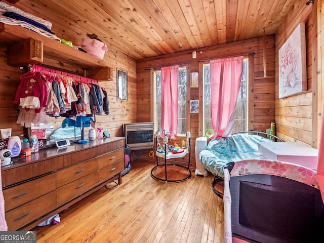 bedroom featuring wood ceiling, wooden walls, light hardwood / wood-style floors, and heating unit