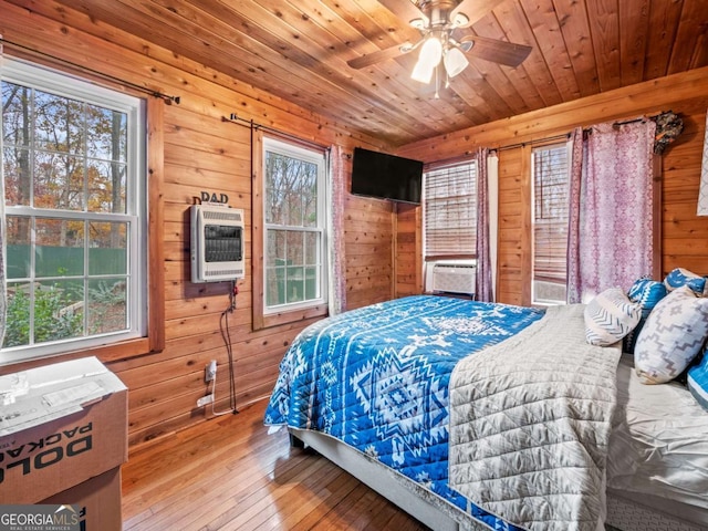 bedroom featuring multiple windows, heating unit, wood ceiling, and wood walls