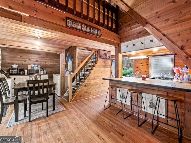 dining room featuring wood ceiling, light hardwood / wood-style flooring, and wood walls