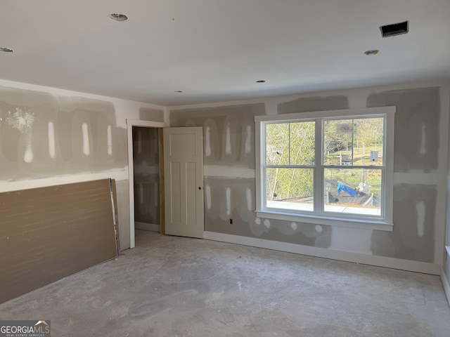 spare room featuring concrete floors and baseboards