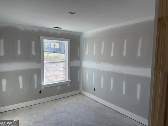 unfurnished room with visible vents, concrete floors, and baseboards