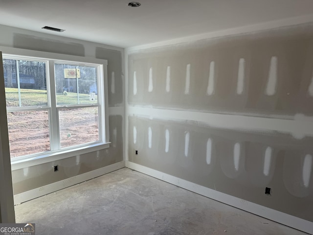 empty room featuring concrete flooring, visible vents, and baseboards