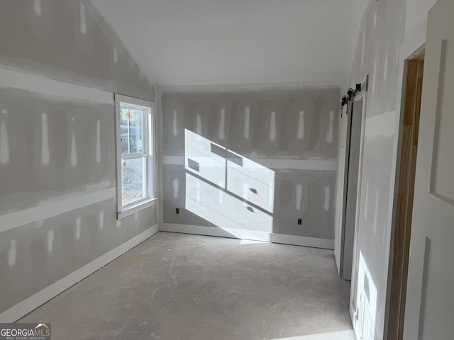 spare room with concrete floors and vaulted ceiling