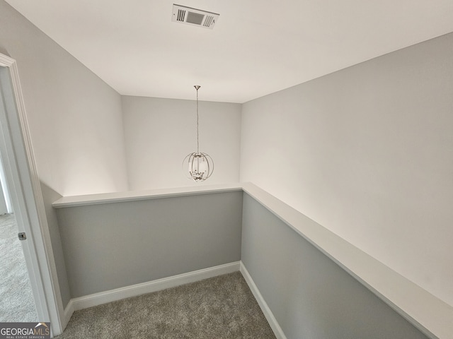 interior space with dark colored carpet and a notable chandelier