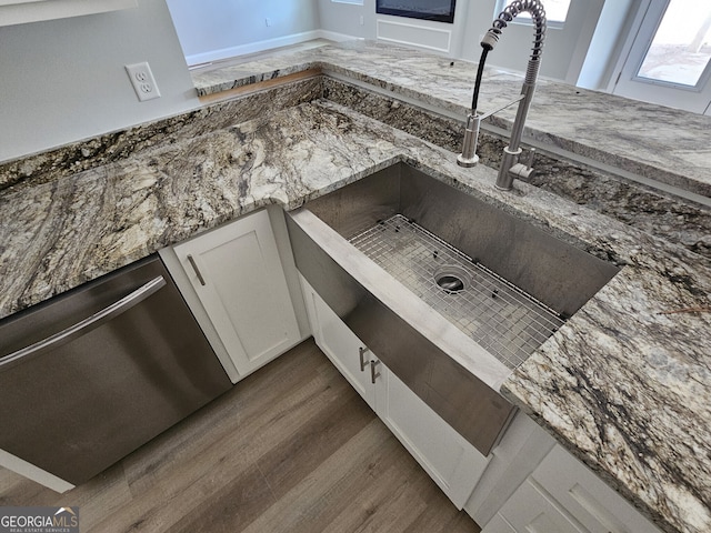 room details featuring dark hardwood / wood-style flooring, dark stone counters, sink, dishwasher, and white cabinetry