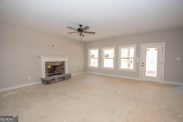 unfurnished living room with ceiling fan and a stone fireplace