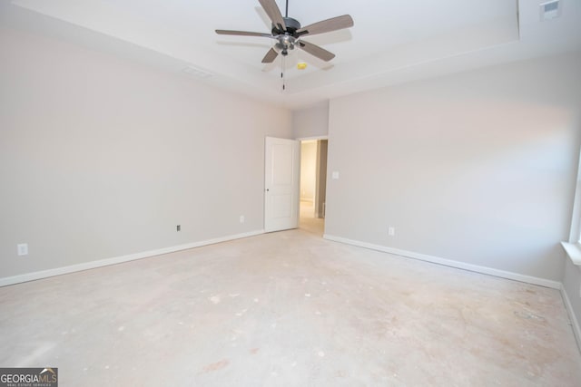 unfurnished room with ceiling fan and a tray ceiling