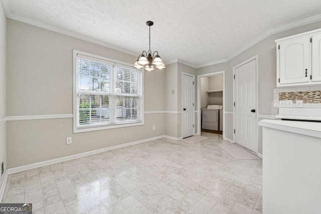 unfurnished dining area featuring ornamental molding, a textured ceiling, washing machine and dryer, and a notable chandelier