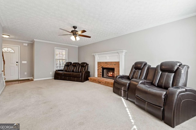 living room featuring a brick fireplace, ornamental molding, a textured ceiling, light colored carpet, and ceiling fan