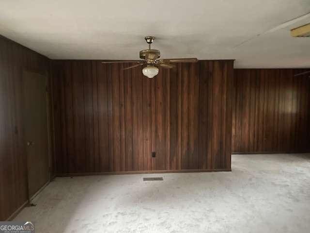 empty room with light colored carpet and wooden walls