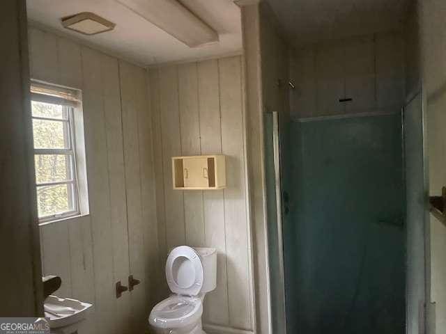 bathroom with wood walls and toilet