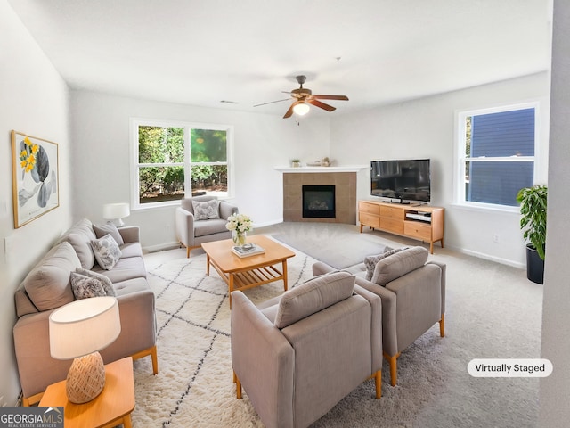 carpeted living room with a tile fireplace and ceiling fan