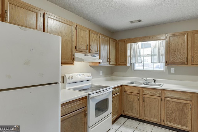 kitchen with light tile patterned flooring, a textured ceiling, white appliances, and sink