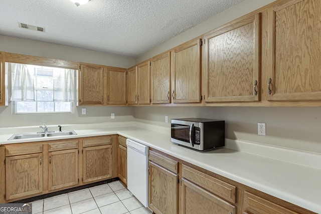 kitchen featuring dishwasher, sink, light tile patterned flooring, and a textured ceiling