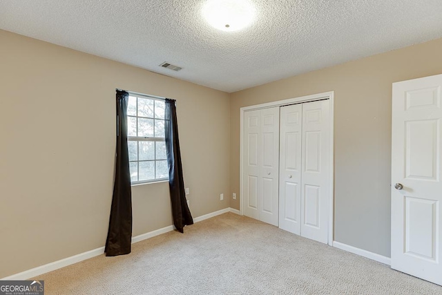 unfurnished bedroom featuring carpet flooring, a closet, and a textured ceiling