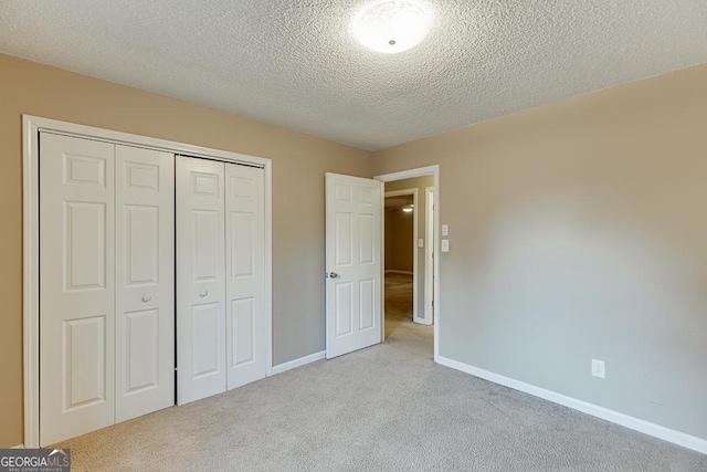 unfurnished bedroom featuring a textured ceiling, light colored carpet, and a closet