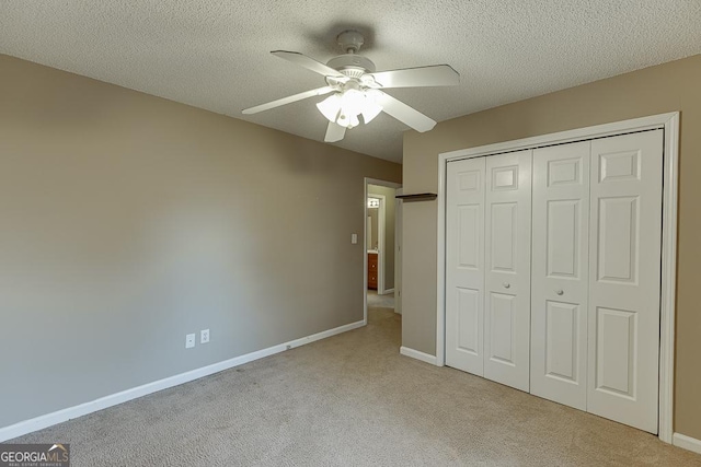 unfurnished bedroom featuring ceiling fan, a closet, light colored carpet, and a textured ceiling