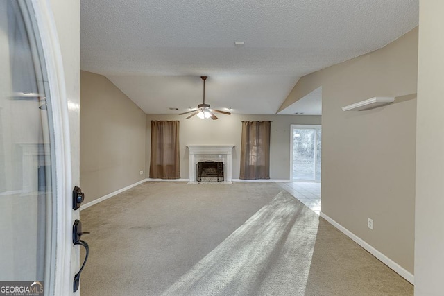 unfurnished living room with a textured ceiling, ceiling fan, light carpet, and lofted ceiling