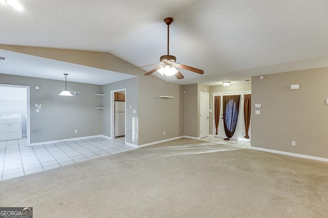 empty room with vaulted ceiling, ceiling fan, a textured ceiling, light colored carpet, and washer / clothes dryer