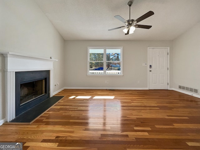 unfurnished living room featuring ceiling fan, wood-type flooring, and a textured ceiling