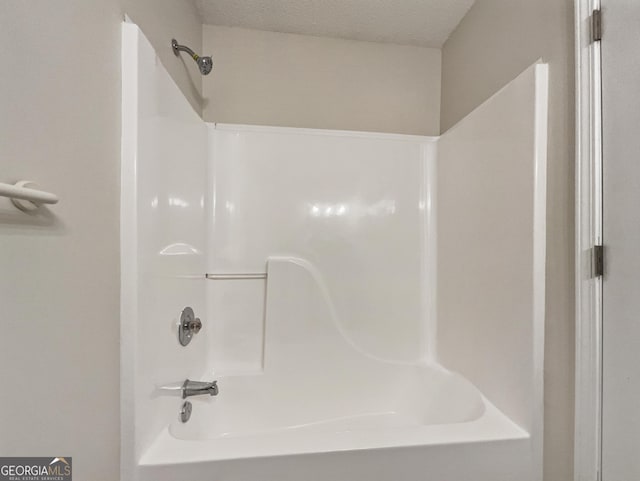 bathroom featuring a textured ceiling and bathing tub / shower combination