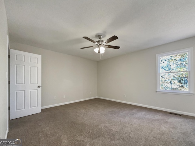 carpeted empty room with ceiling fan and a textured ceiling