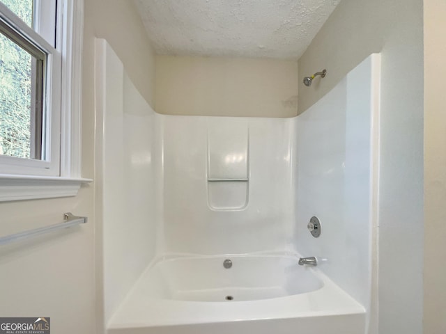 bathroom with  shower combination and a textured ceiling