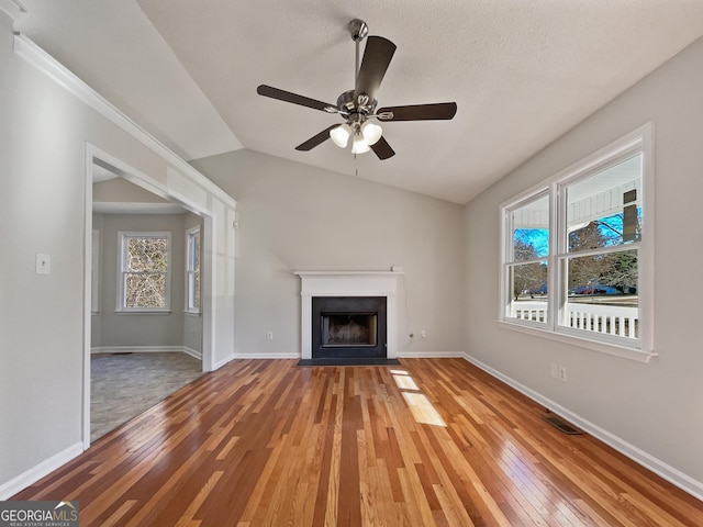 unfurnished living room featuring a textured ceiling, ceiling fan, vaulted ceiling, and hardwood / wood-style flooring