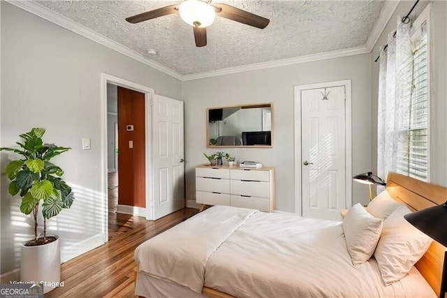 bedroom featuring ceiling fan, crown molding, wood-type flooring, and a textured ceiling