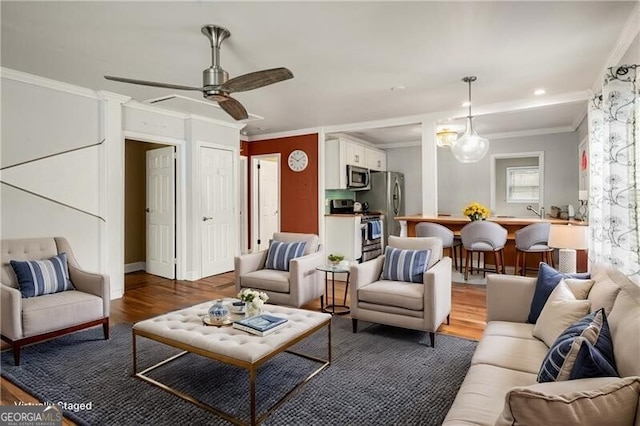 living room featuring dark hardwood / wood-style floors, ceiling fan, and crown molding