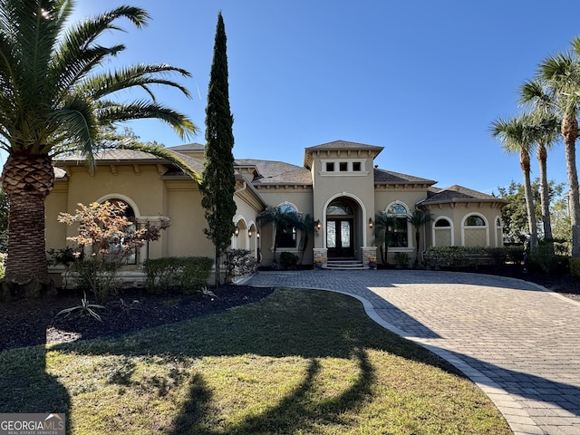 mediterranean / spanish-style home with a front yard and french doors